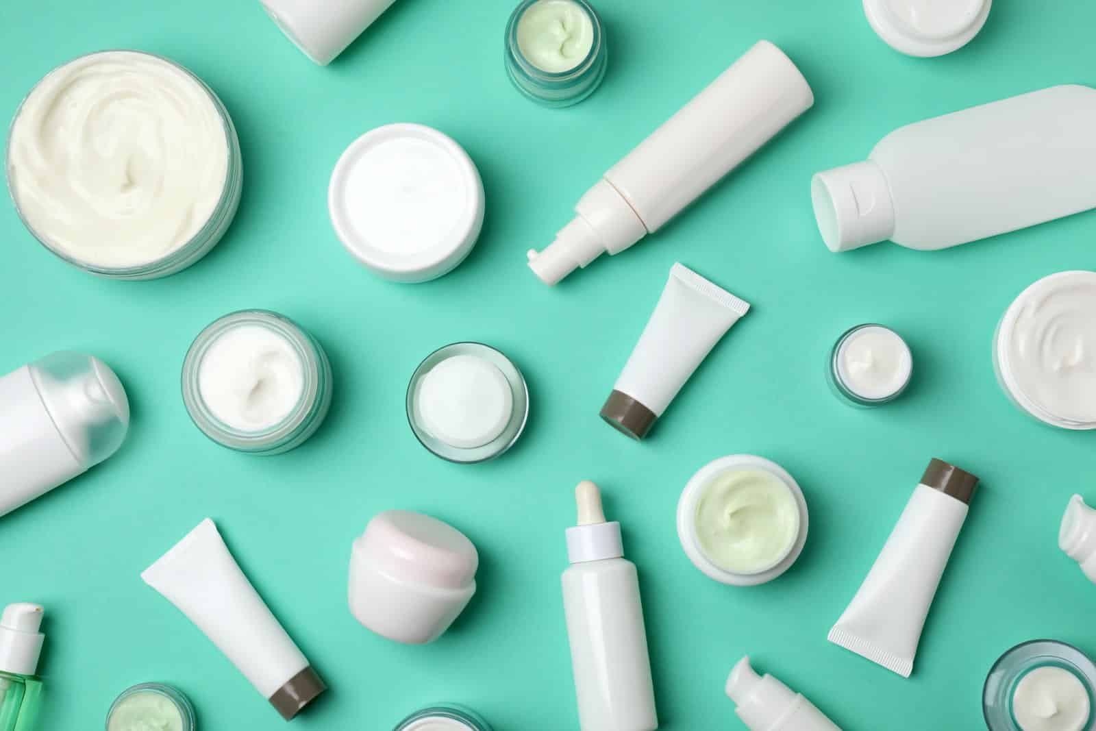 skincare products and creams and tubes on green turquoise background