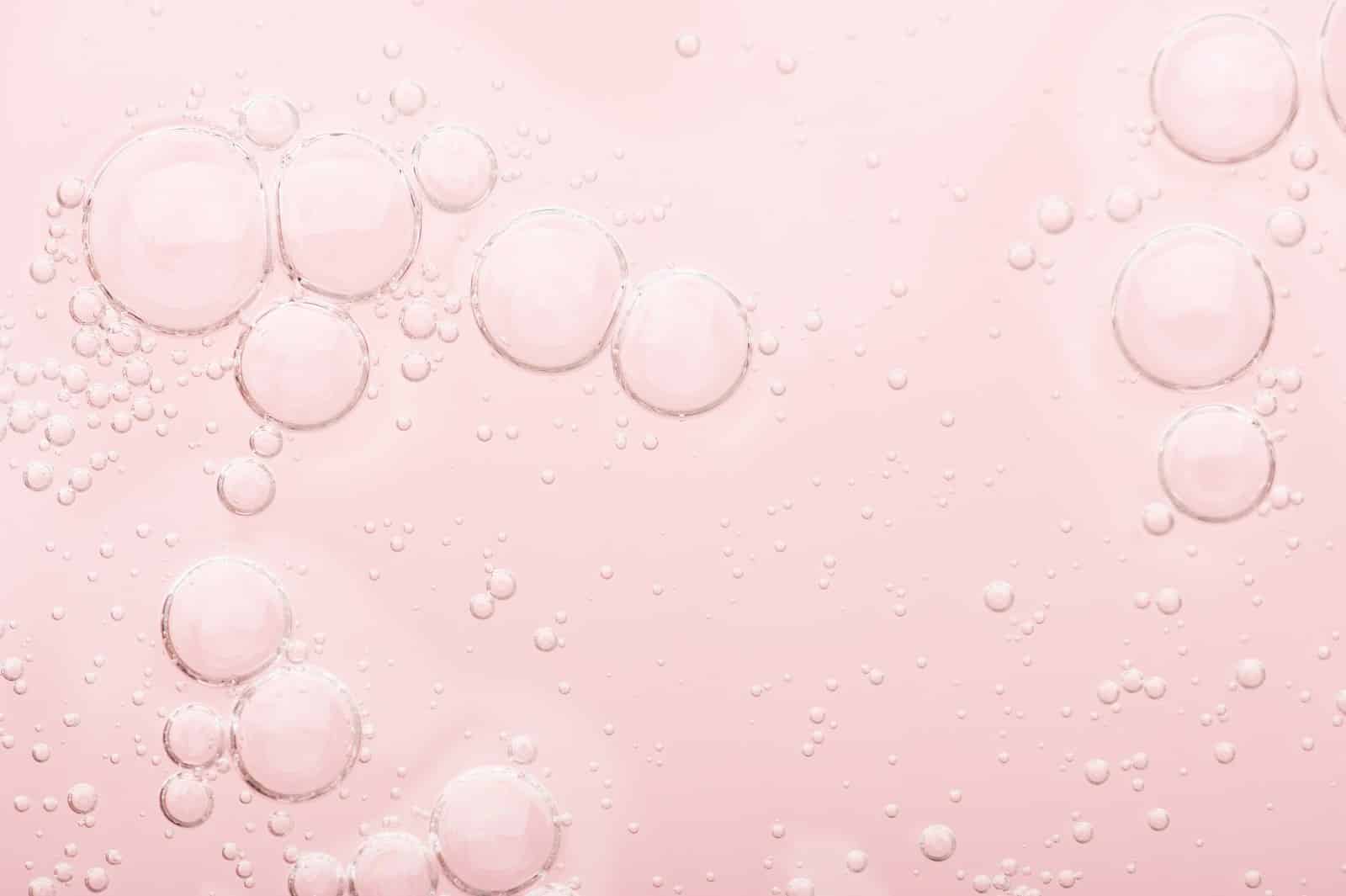 moisturizer skin cream and serum droplets on pink background