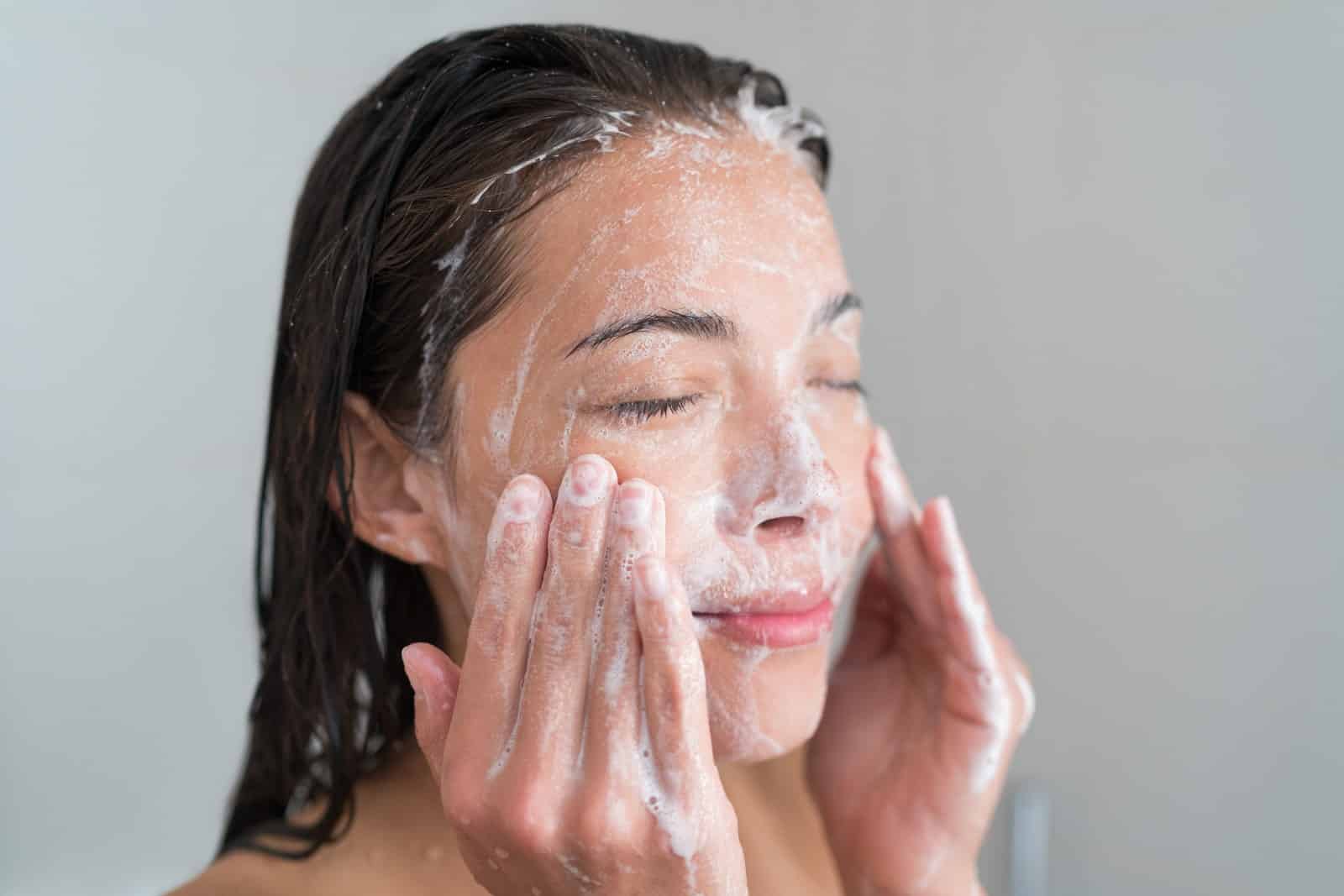 Woman with black hair exfoliating her skin