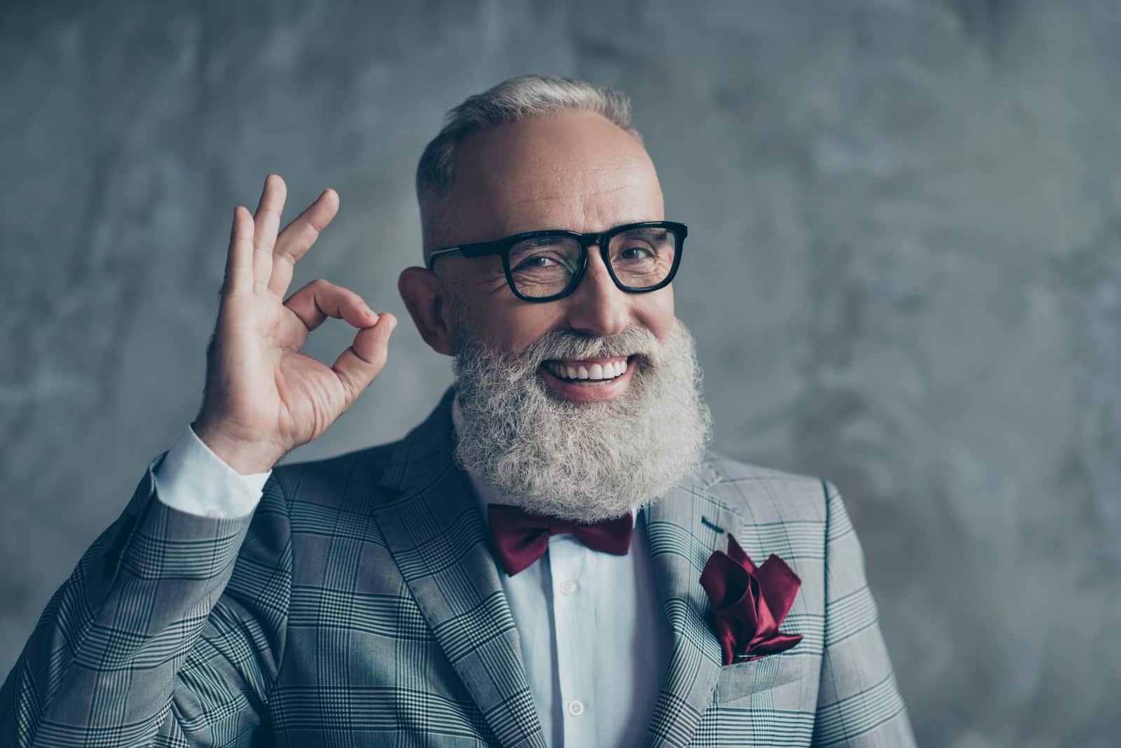 Happy old man with gray beard and costume winking